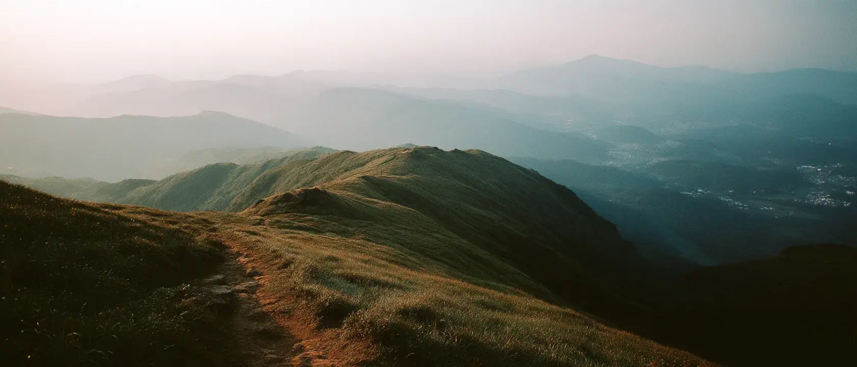 A trail winding through valleys and ridges far below a summit at golden hour